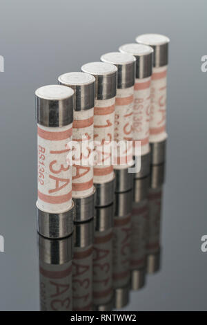 Domestic appliance electrical 13 Amp fuses (Ceramic Cartridge type) on reflective black background. Metaphor electrical safety. 25mm L x 6.3mm D Stock Photo
