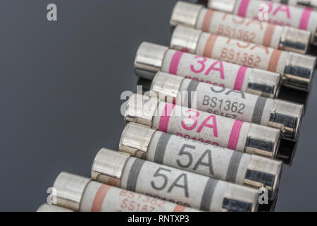 Domestic appliance 3A, 5A & 13A electrical fuses (Ceramic Cartridge type) on reflective black background. Metaphor electrical safety. 25mm L x 6.3mm D Stock Photo
