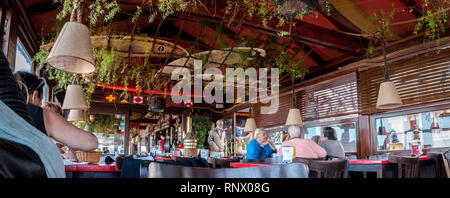 VILLA GESELL, BUENOS AIRES, ARGENTINA - MARCH 21, 2018: people chating inside beach restaurant and bar with surf tables on the ceiling. Translation ex Stock Photo