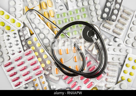 Stethoscope on blisters with colorful pills. A lot of medicine. Stock Photo