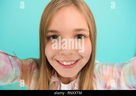 Let me take selfie. Child girl hold smartphone takes photo. Child kid happy face. Video call concept. Video conference camera. Girl long hair hold smartphone taking selfie. Selfie for social networks. Stock Photo