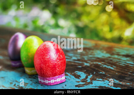 Three colorful easter eggs on blue wooden table. Happy Easter. Village life. Christian tradition. Easter composition. Easter concept. Traditional deco Stock Photo