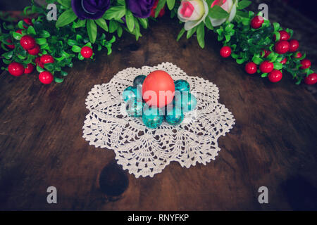 easter eggs on the background of wooden boards. Red chicken egg surrounded by small blue quail eggs on a white tablecloth. Decorations for the celebra Stock Photo