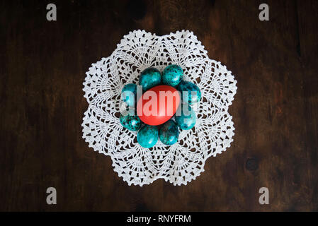 easter eggs on the background of wooden boards. Red chicken egg surrounded by small blue quail eggs on a white tablecloth. Decorations for the celebra Stock Photo