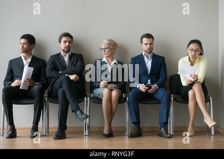 Diverse businesspeople applicants sitting in row waiting for job interview Stock Photo
