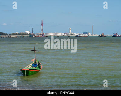 Single fishing boat on the beach with a growing industrial estate in the background in Map Ta Phut, Rayong Province in Thailand Stock Photo