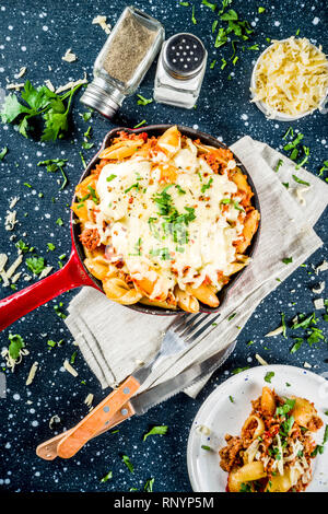 Baked creamy pasta casserole, mac and cheese with minced meat, italian ground beef bolognese casserole, dark blue concrete background copy space Stock Photo