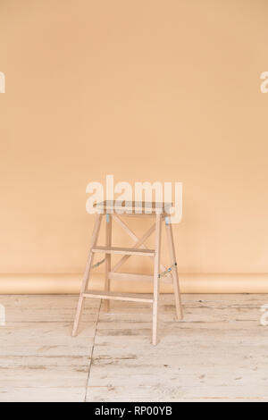 The working space of the photo studio with a beige paper background and chair. Stock Photo