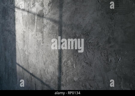 Decorative plaster. Artificial concrete. The texture of the gray concrete wall with a glint of light from the window. Stock Photo