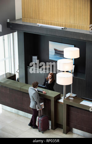 Female receptionist talking on telephone while businessman standing at counter Stock Photo