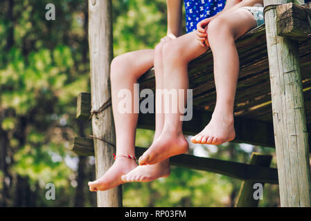 Low section of brother and sister relaxing in forest Stock Photo