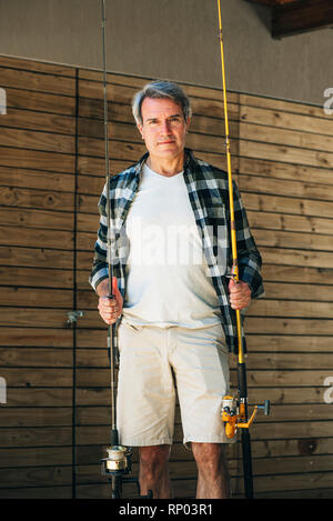 Mature man holding fishing rods Stock Photo