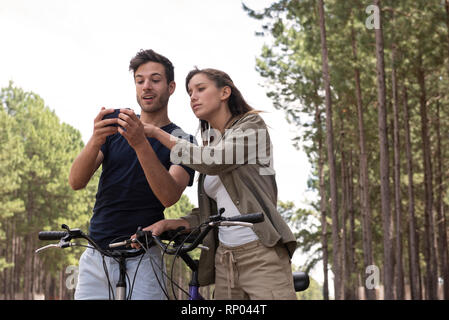 Young couple using smart phone in pine forest Stock Photo
