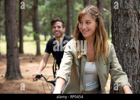 Young couple cycling in pine forest Stock Photo