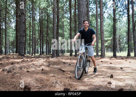 Young man cycling in pine forest Stock Photo
