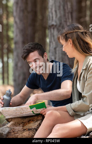 Young couple reading map while sitting in the forest Stock Photo