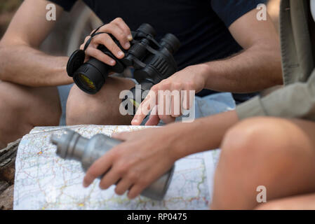 Young couple reading map while sitting in the forest Stock Photo