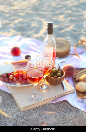 Picnic outdoor with rose wine fruits meat and cheese. Sunset Stock Photo
