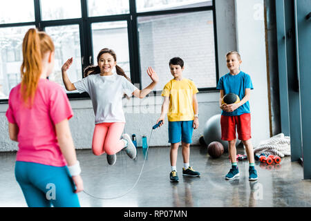 Preteen kids jumping with skipping rope in gym Stock Photo