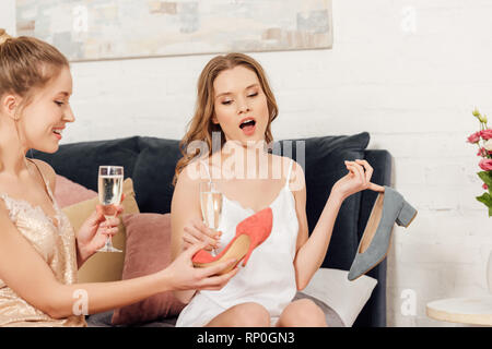 beautiful girls with champagne glasses choosing shoes during pajama party Stock Photo