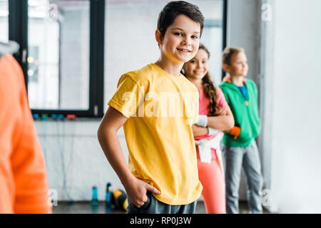 Smiling brunette boy posing in gym with friends Stock Photo
