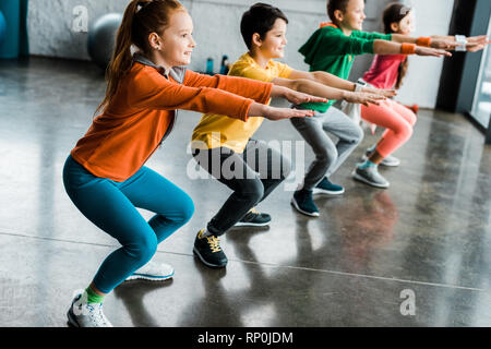 Preteen kids doing squats in gym together Stock Photo