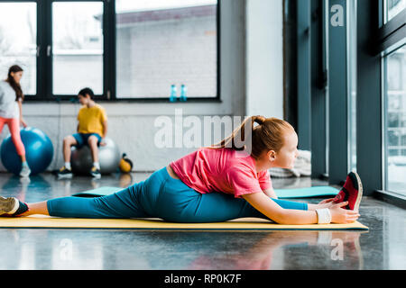 Kid in sportswear doing twine in gym Stock Photo