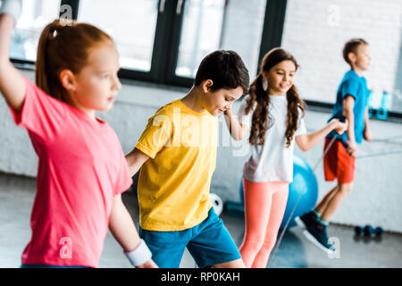 Preteen children jumping with skipping ropes in gym Stock Photo