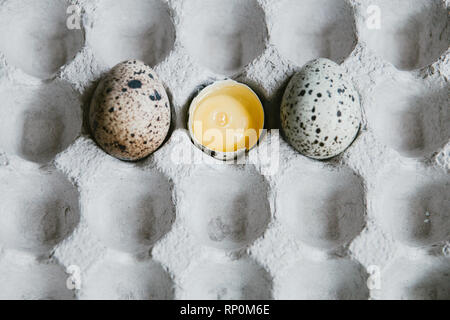Textured spring background with small quail eggs. Eco products. Quail eggs in cardboard packaging. Yolk of quail eggs without shell Stock Photo