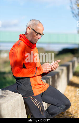 Senior runner in nature with smartphone. Stock Photo