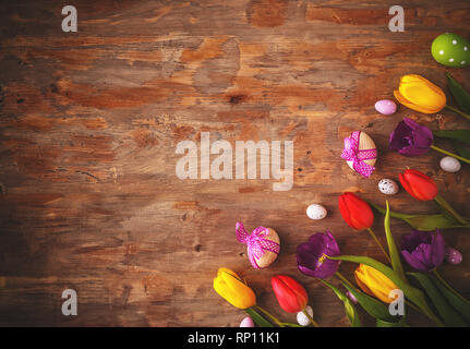 Easter greeting card with eggs and tulips on wooden background. Top view with space for your greetings Stock Photo