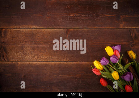 Overhead shot a bouquet of colourful tulips over a rustic wood table Stock Photo