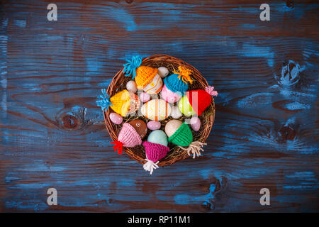 Easter basket filled with colorful eggs on a blue wooden background Stock Photo