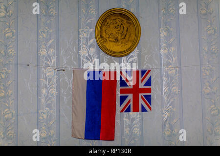 The two flags of UK and Russia are hung underneath a golden plate with Siberian tiger in its centre. Stock Photo