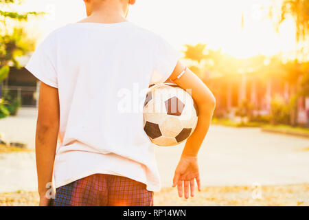 sport outdoor picture of kids having fun playing soccer football for exercise under the twilight sunset sky. Stock Photo