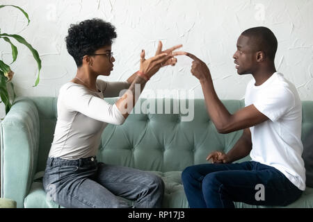 Black african couple quarrelling sitting on couch Stock Photo