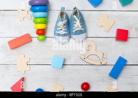 Children's sneakers and wooden educational toys on a wooden background. Flat lay Stock Photo