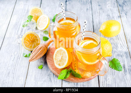 Iced summer drink, tea with lemon slices and mint, rustic wooden background copy space Stock Photo