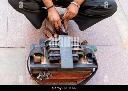 Indian shoemaker or cobbler in street workshop repairing shoes and other leather items. Stock Photo