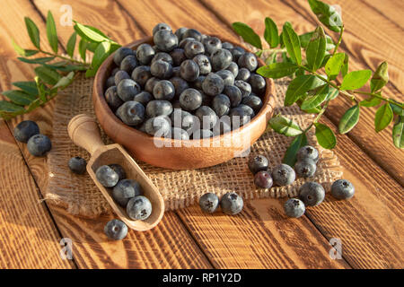 Fresh Blueberries In Wooden Bowl On Old Wooden Planks Background. Outdoor Image Shot In The Sunshine Stock Photo