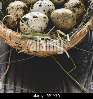 Fresh organic quail eggs in small wicker basket on rustic kitchen table. Space for text Stock Photo
