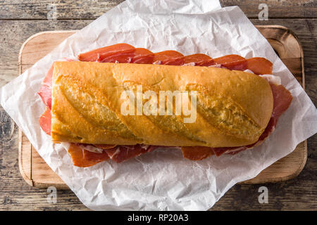 Spanish serrano ham sandwich on wooden table. Top view Stock Photo
