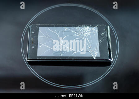 broken phone rests on a black frosted glass, in the center of the circle. background Stock Photo