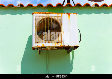 Old rusty air conditioning hanged on the wall on the old house. Air conditioner on the wall at the sunny day Stock Photo
