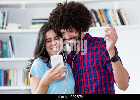 Hipster couple streaming song with phone and listening music indoors at home Stock Photo