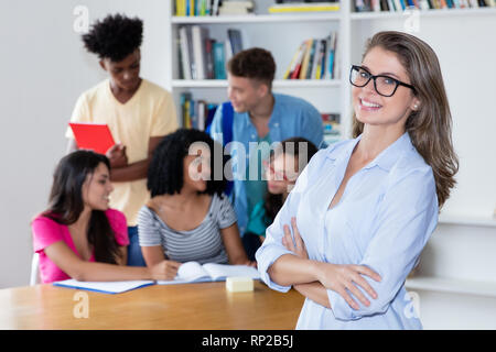 Female teacher with eyeglasses and international students at classroom at university Stock Photo