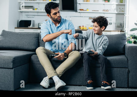 happy latin father giving fist bump to son after playing video game at home Stock Photo