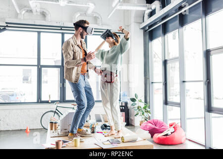 female and male designers wearing vr headset, gesturing with hands and having virtual reality experience in loft office Stock Photo