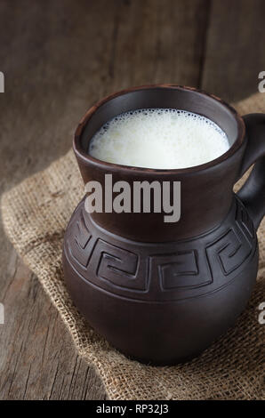 Fresh milk in a clay pitcher on wooden background. Stock Photo