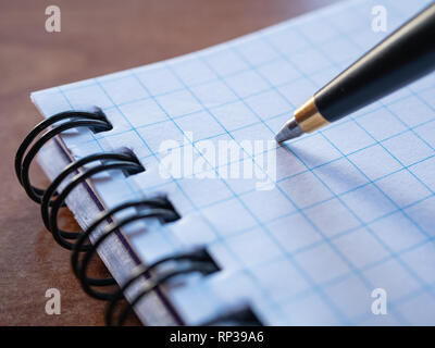 macro extreme closeup image of pen with squared notebook binded with spiral Stock Photo